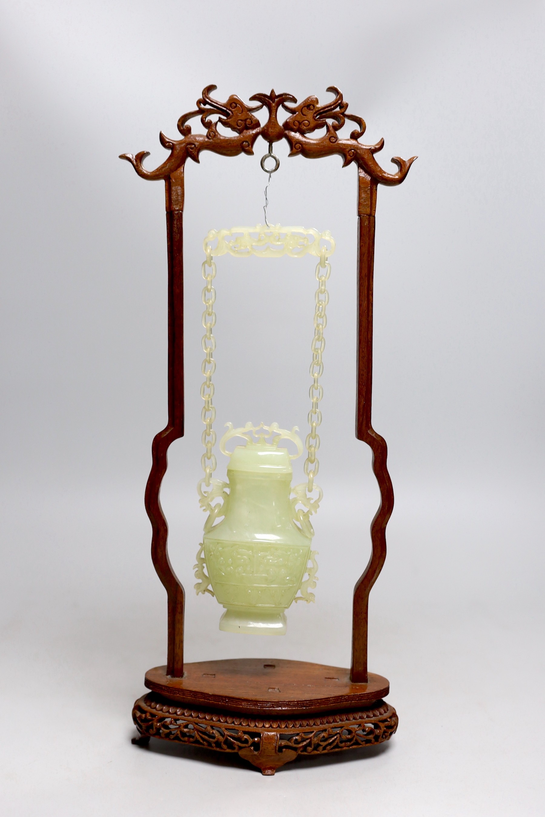 A Chinese bowenite jade hanging vase and cover together with a carved hard wood stand, one foot missing, 42cm tall